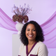 Portrait of a smiling woman with a warm expression, against a soft lavender and white background.