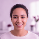 Portrait of a smiling young woman, diverse, with a warm and trustworthy expression, against a soft, blurred background.